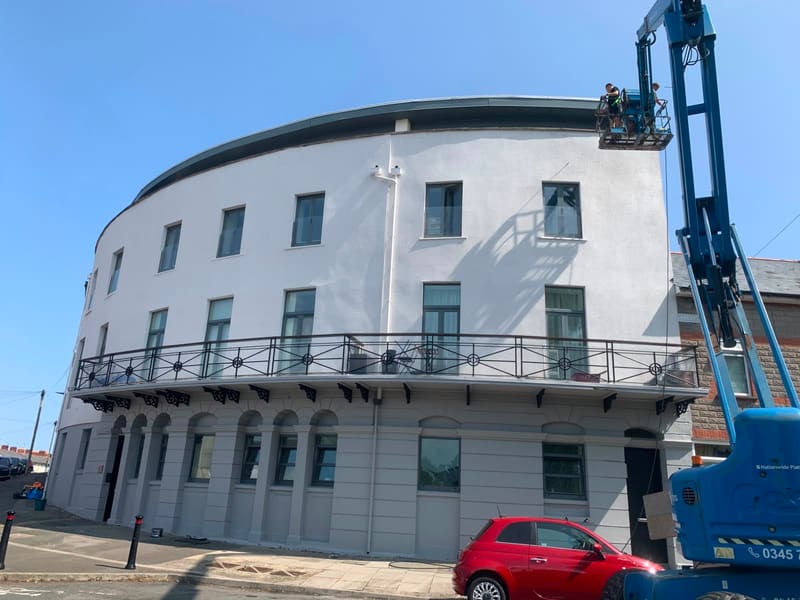 After: Workers on a cherry picker painting a curved white building