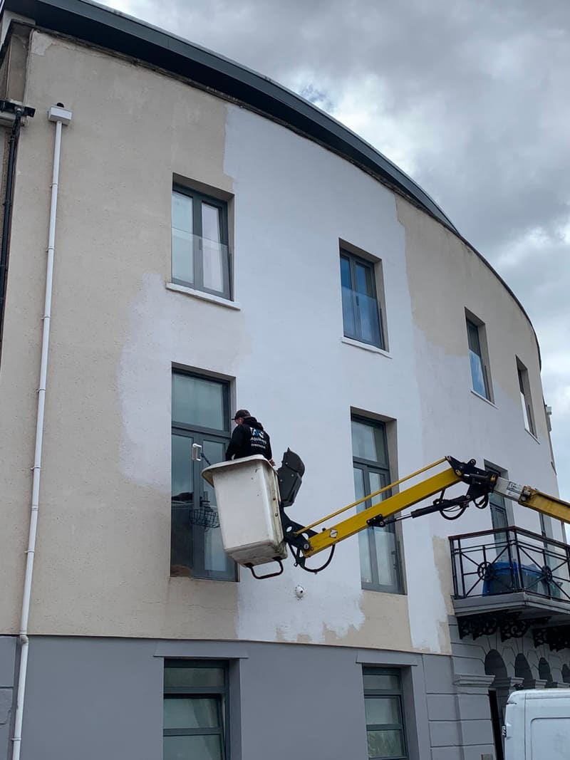 Before: Worker in a cherry picker painting a building exterior white