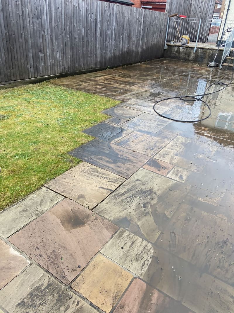 Before: wet, dirty stone patio slabs next to a lawn