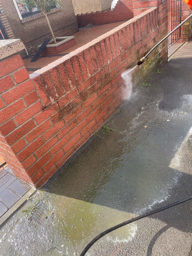 Power washing a dirty brick wall and driveway
