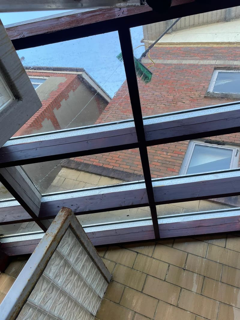 Cleaning a glass roof with a brush from above