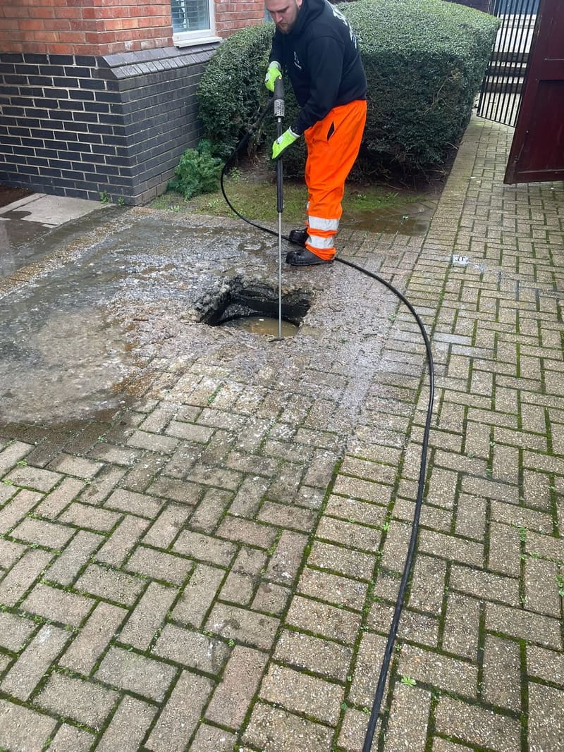 Jet washing a blocked drain on a driveway