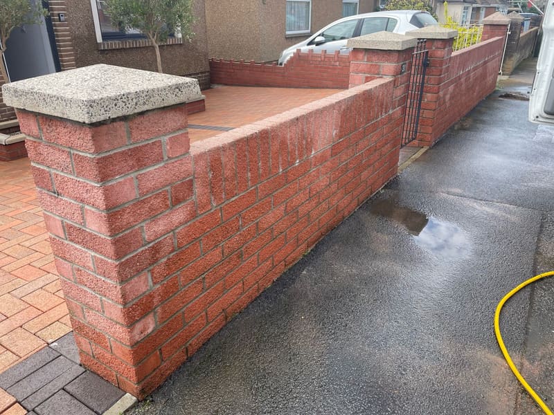 Red brick garden wall and driveway paving outside a house