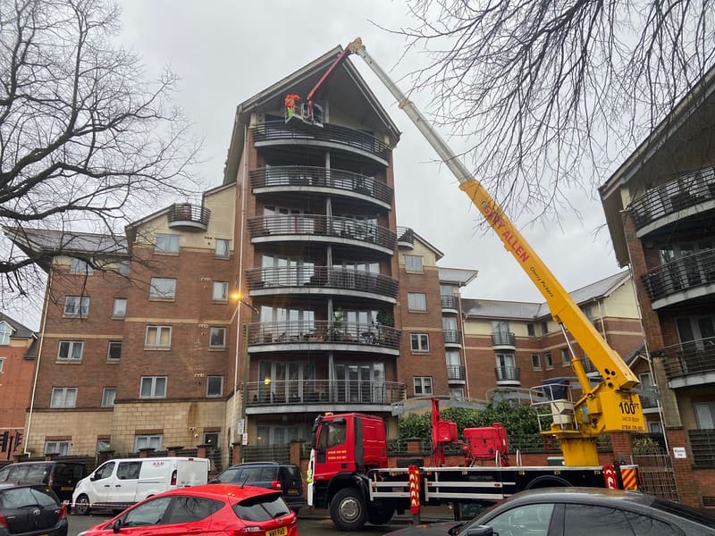 Cherry picker basket raised to the gutters of a brick apartment building