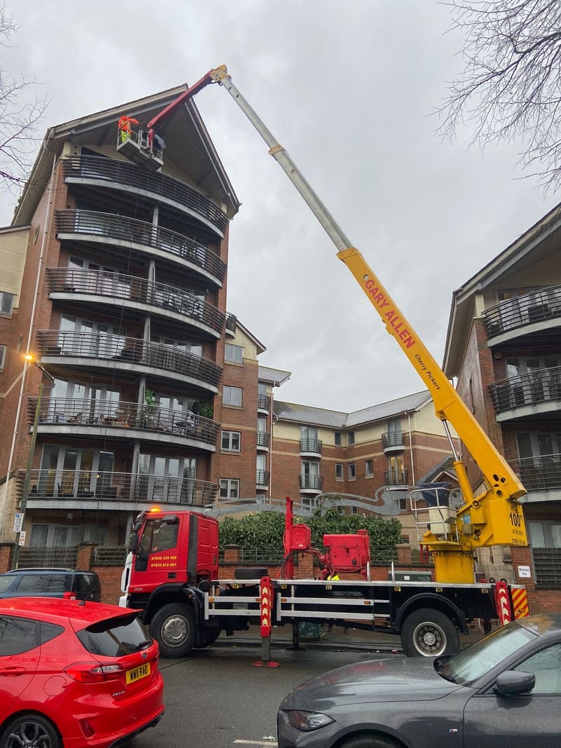 Cherry picker basket working at roof level on an apartment building