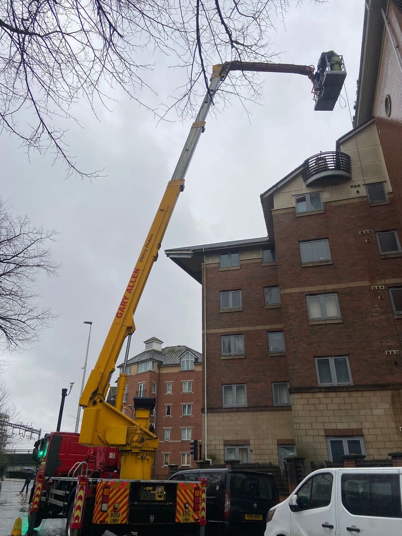 Cherry picker lifting a worker to a building's roofline