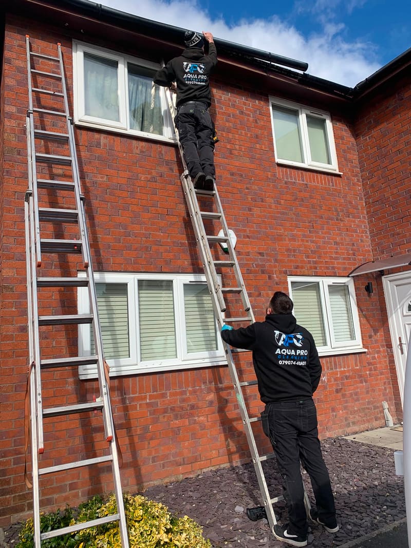 Aqua Pro Cleaning technicians cleaning gutters on a house