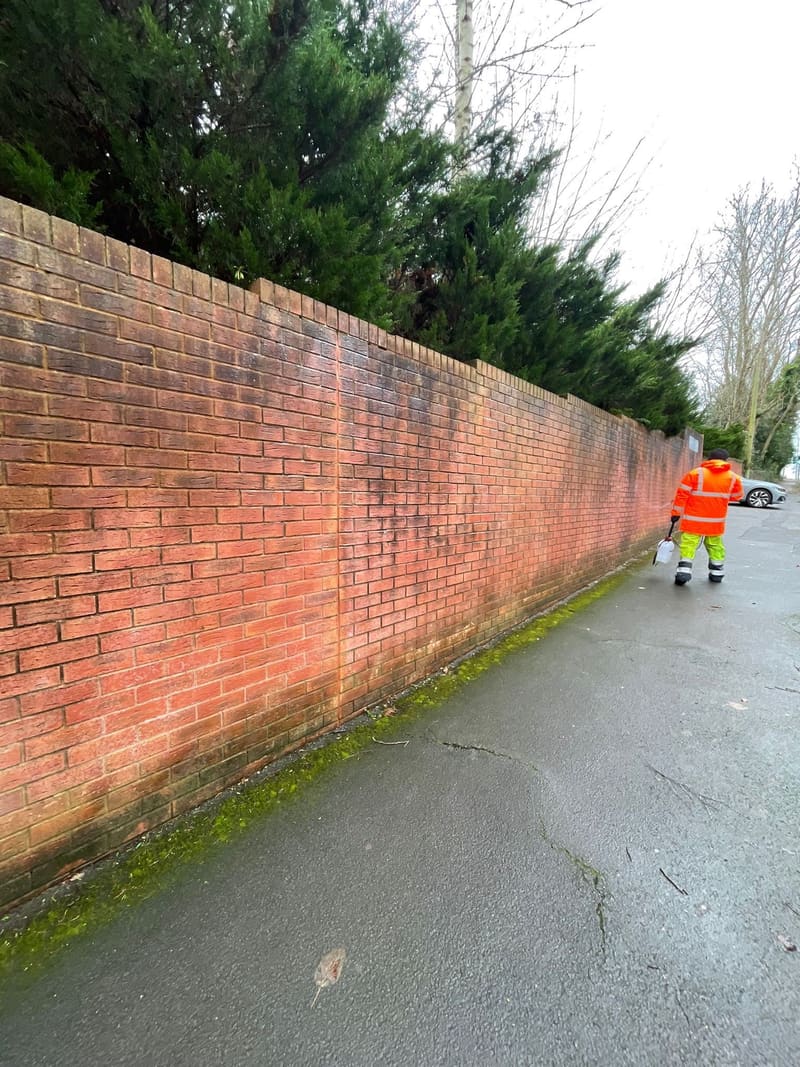 Worker in high-visibility gear by a brick wall