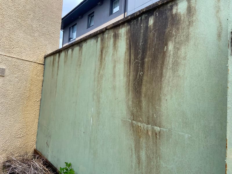 Stained exterior wall with dark water run-off marks before cleaning