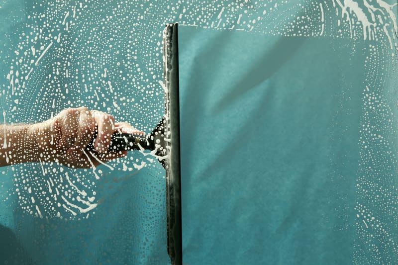 Squeegee wiping soap suds off a window pane